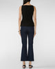 A woman shown from the back wearing a sleeveless black top and dark navy flared pants, standing against a light gray studio background.