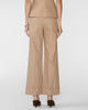 A model shown from the back wearing beige wide-leg cropped trousers, a matching beige top, and dark brown pointed-toe heels against a light gray studio background.