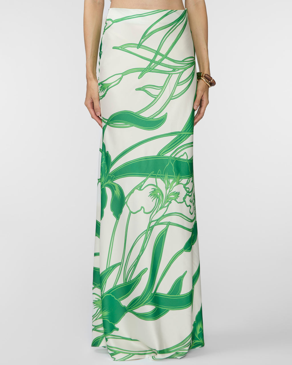 Long white skirt with green leaf pattern worn by a person on a white background