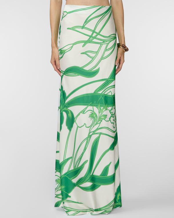 Long white skirt with green leaf pattern worn by a person on a white background